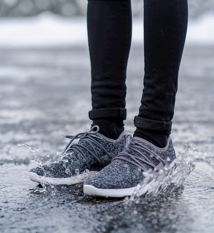 Person splashing in a puddle to show off Vessi waterproof shoes